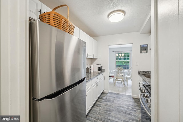 kitchen featuring dark stone countertops, white cabinetry, dark wood-type flooring, stainless steel appliances, and a textured ceiling