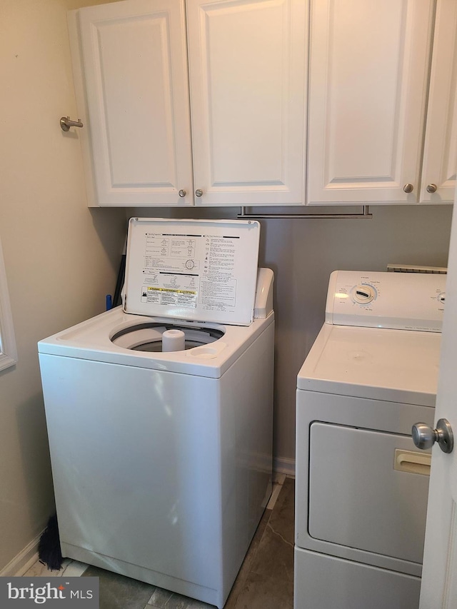 clothes washing area with cabinets and washing machine and dryer