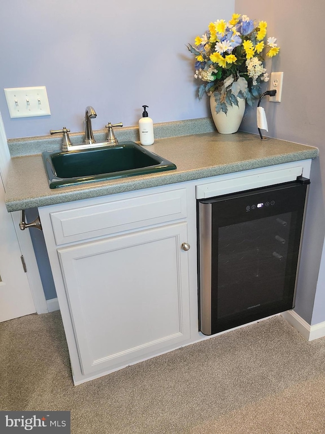 interior space with white cabinets, beverage cooler, light colored carpet, and sink