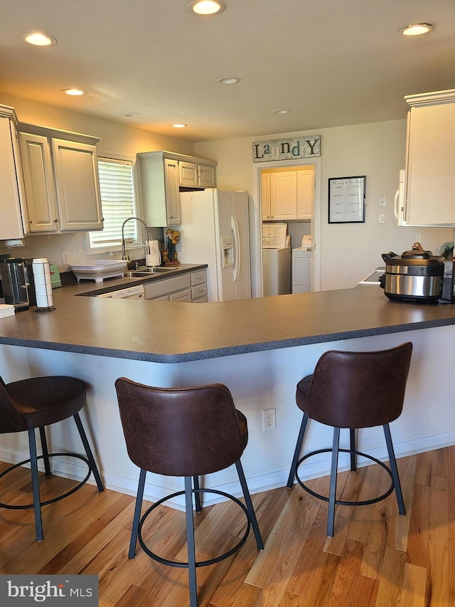 kitchen with kitchen peninsula, white refrigerator with ice dispenser, and light hardwood / wood-style flooring