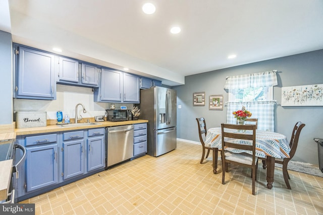 kitchen with blue cabinetry, stainless steel appliances, and sink