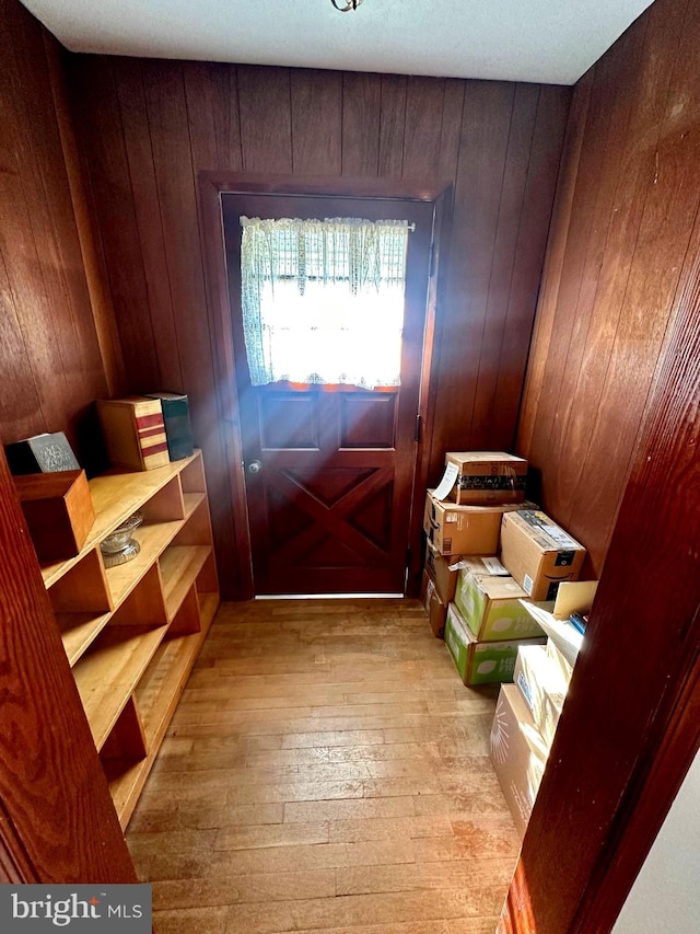 entryway with wood walls and light hardwood / wood-style flooring