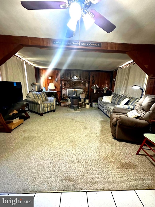 living room featuring ceiling fan, a wood stove, and wooden walls