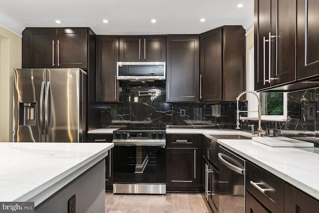 kitchen with light hardwood / wood-style flooring, stainless steel appliances, decorative backsplash, and light stone countertops