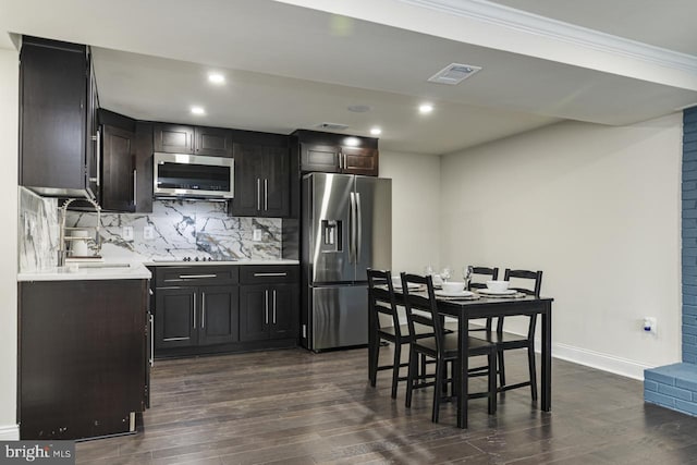 kitchen featuring ornamental molding, stainless steel appliances, dark wood-type flooring, and tasteful backsplash