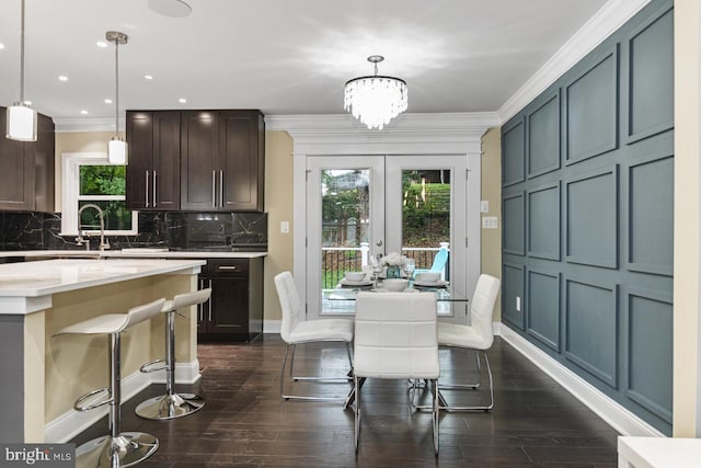 dining space with a notable chandelier, sink, ornamental molding, and dark hardwood / wood-style flooring