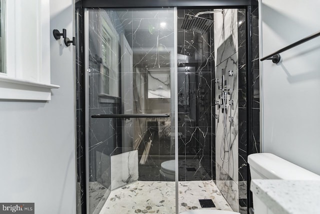 bathroom with a shower with door and toilet