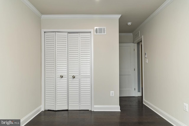 unfurnished bedroom featuring a closet, dark wood-type flooring, and crown molding