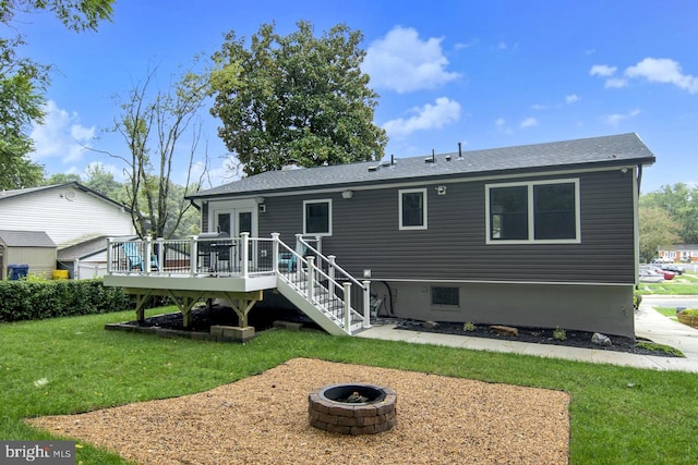 back of property featuring a yard, a wooden deck, and a fire pit