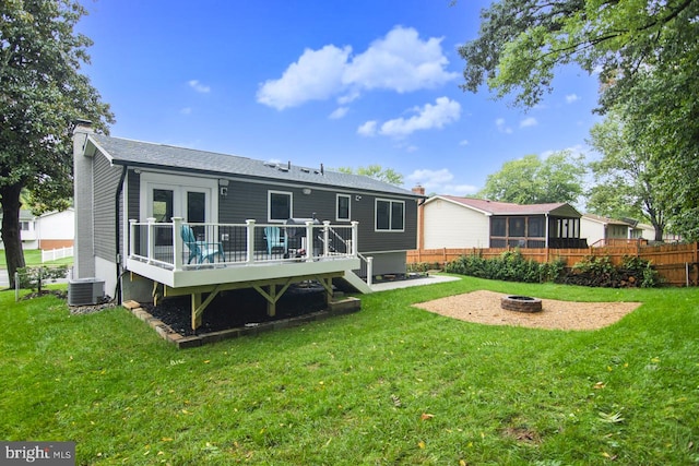 back of house featuring a fire pit, central AC unit, a deck, and a yard