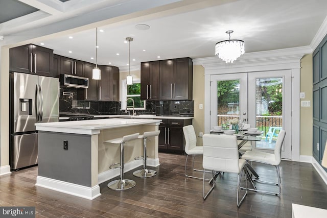 kitchen featuring pendant lighting, a kitchen island, appliances with stainless steel finishes, a kitchen breakfast bar, and dark hardwood / wood-style flooring