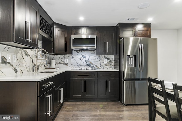 kitchen featuring sink, dark brown cabinets, backsplash, stainless steel appliances, and dark hardwood / wood-style floors