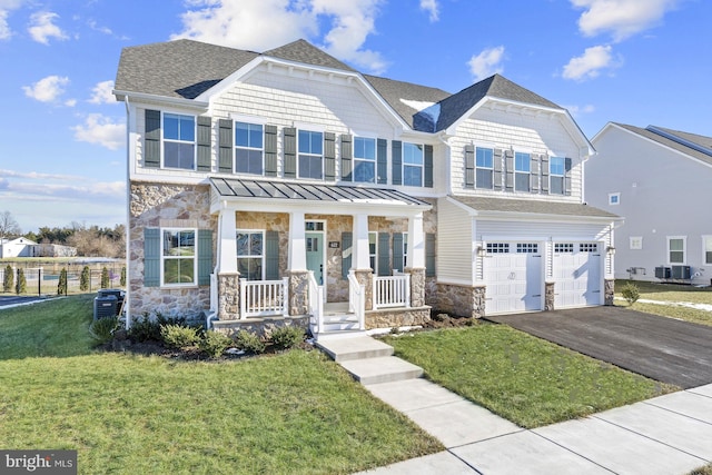 view of front of home with a front lawn, driveway, stone siding, a porch, and a garage