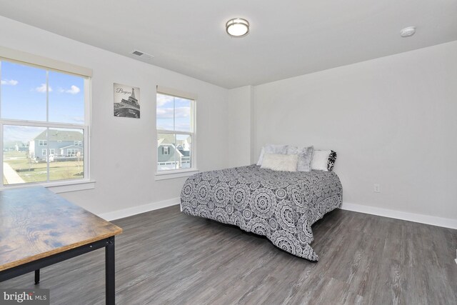 bedroom with multiple windows and dark hardwood / wood-style flooring