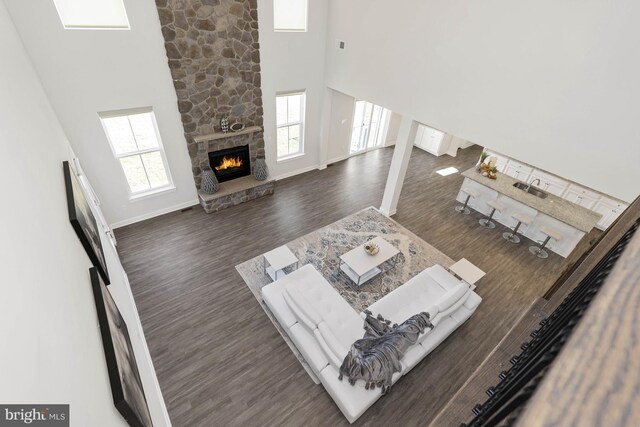 living room featuring plenty of natural light, dark hardwood / wood-style flooring, a fireplace, and a high ceiling