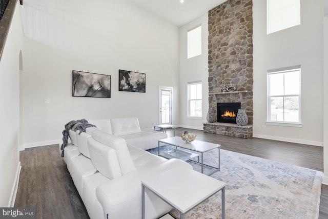 living room featuring a towering ceiling, dark hardwood / wood-style floors, and a healthy amount of sunlight