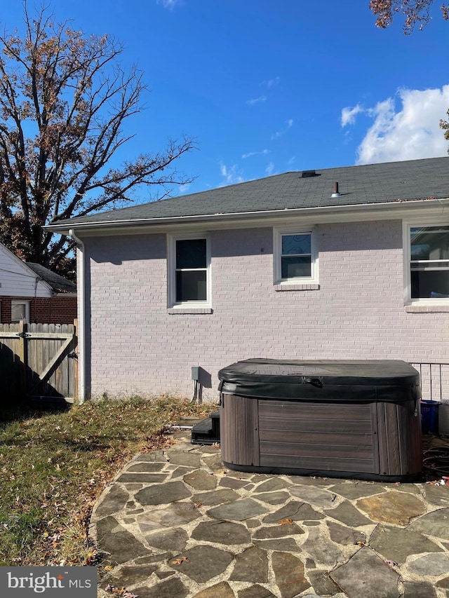 view of side of property with a hot tub and a patio area