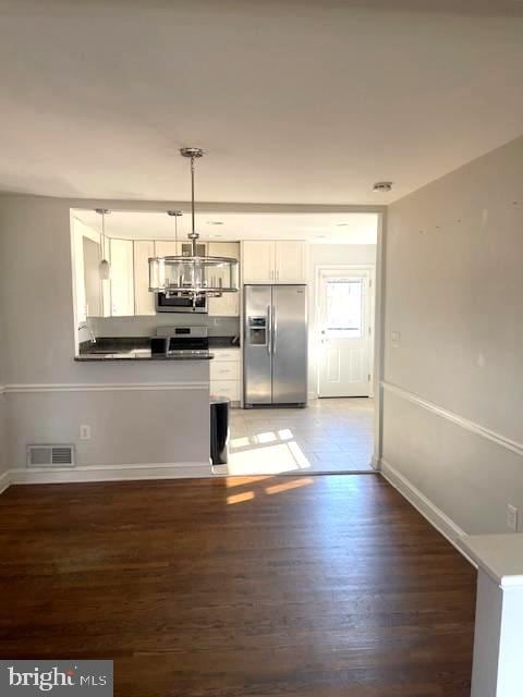 kitchen with stainless steel appliances, dark hardwood / wood-style floors, white cabinets, and pendant lighting