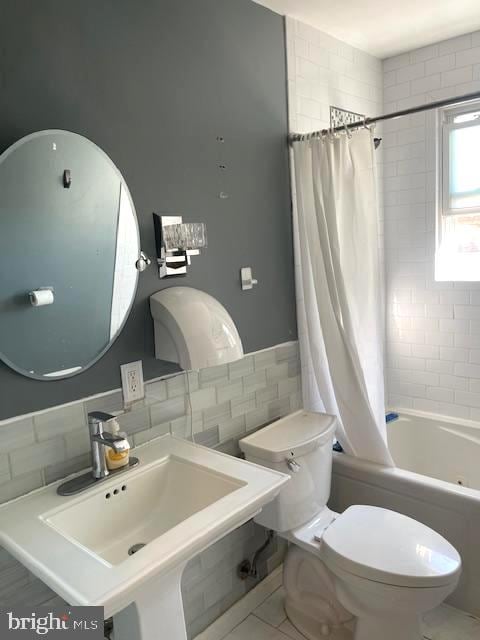 full bathroom featuring tile walls, shower / bath combination with curtain, tile patterned floors, sink, and toilet