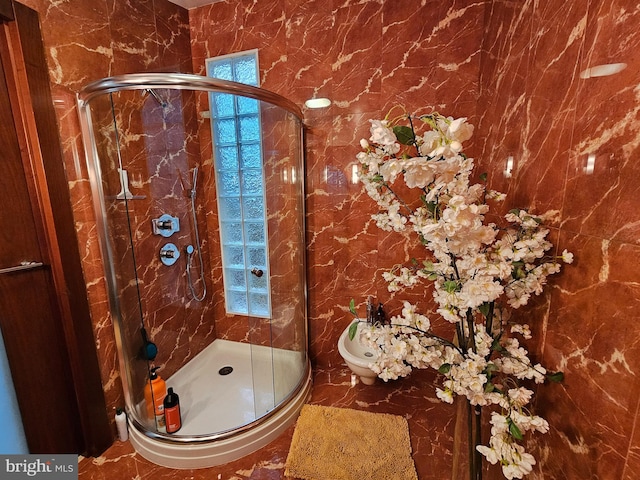 bathroom featuring a wealth of natural light, a bidet, and a shower with shower door