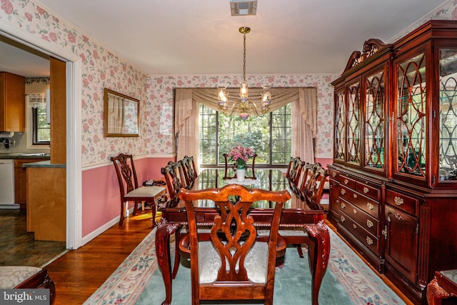 dining area with dark hardwood / wood-style floors and an inviting chandelier