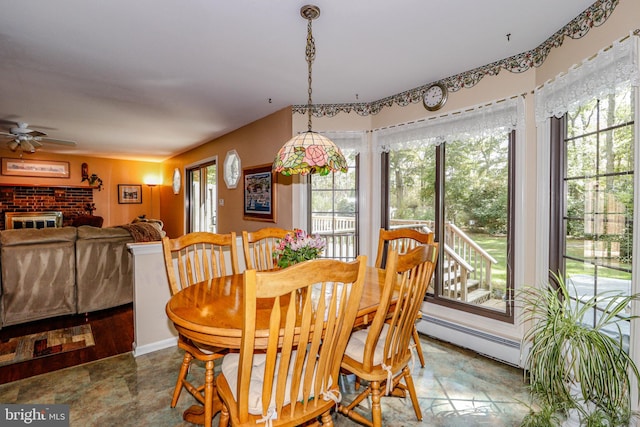 dining area featuring a brick fireplace, ceiling fan, a healthy amount of sunlight, and a baseboard radiator