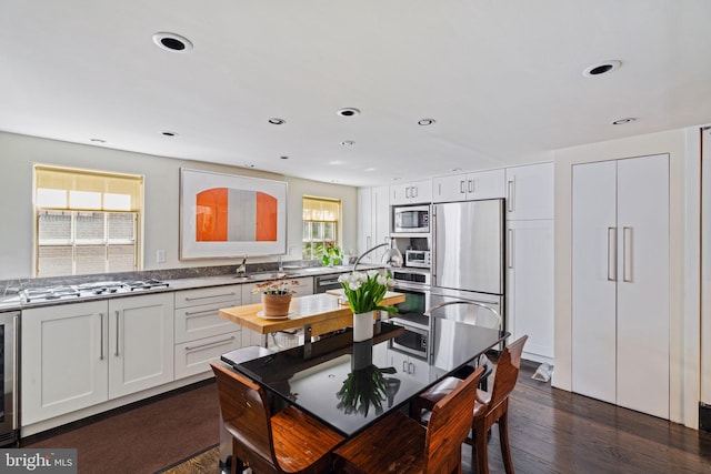 kitchen with appliances with stainless steel finishes, white cabinetry, wine cooler, dark hardwood / wood-style floors, and sink