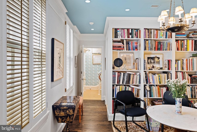 living area featuring crown molding, dark hardwood / wood-style floors, and a notable chandelier