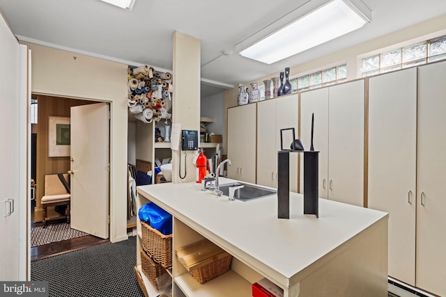 kitchen featuring carpet floors, a baseboard radiator, sink, and white cabinetry