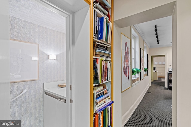 hallway with carpet floors, crown molding, and track lighting