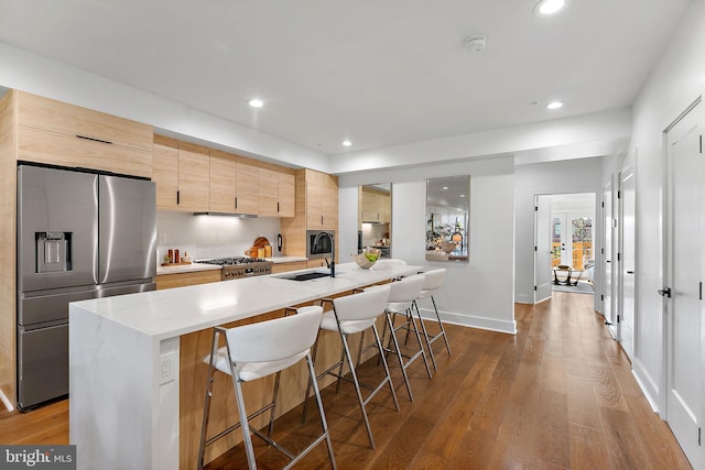 kitchen featuring a kitchen island with sink, sink, stainless steel appliances, and dark hardwood / wood-style flooring