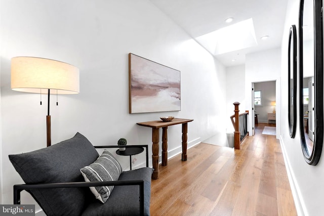 sitting room with light hardwood / wood-style floors and a skylight