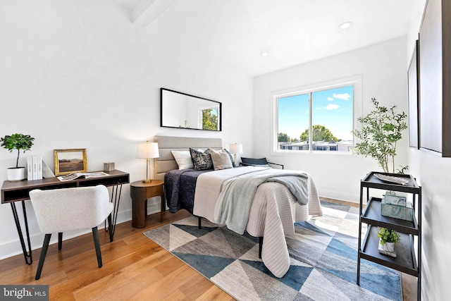 bedroom featuring light hardwood / wood-style flooring and beam ceiling