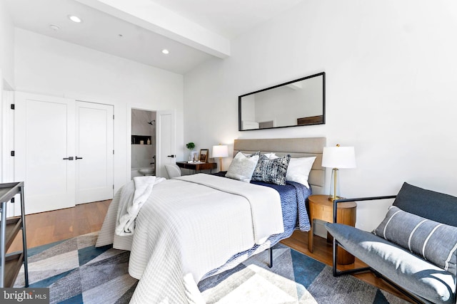 bedroom with beam ceiling and dark hardwood / wood-style floors