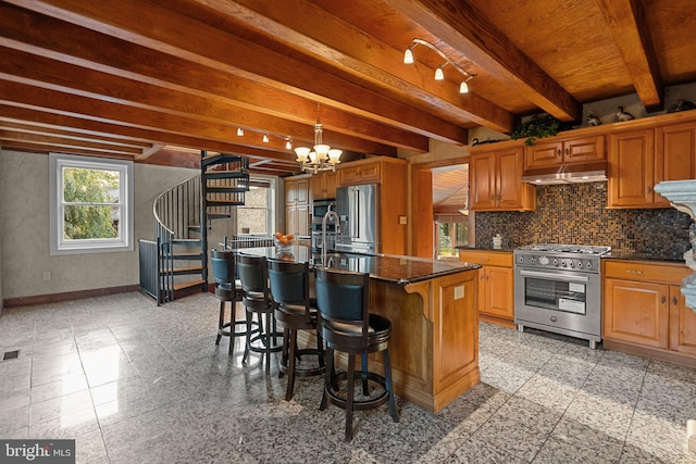 kitchen featuring a kitchen island with sink, tasteful backsplash, a notable chandelier, a kitchen breakfast bar, and appliances with stainless steel finishes