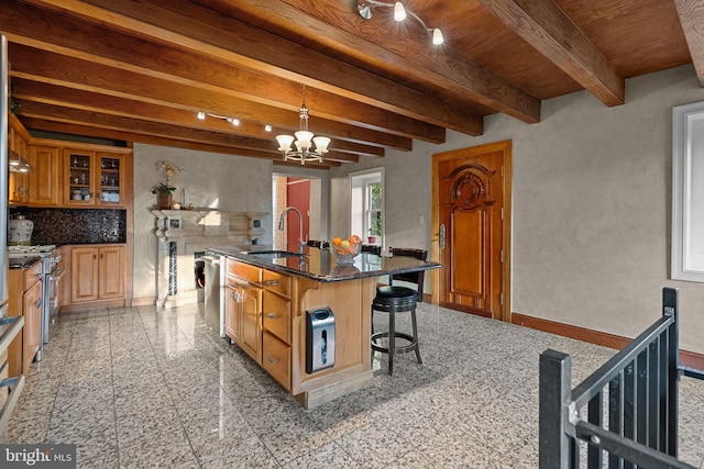 kitchen featuring a breakfast bar, pendant lighting, a kitchen island with sink, sink, and beam ceiling