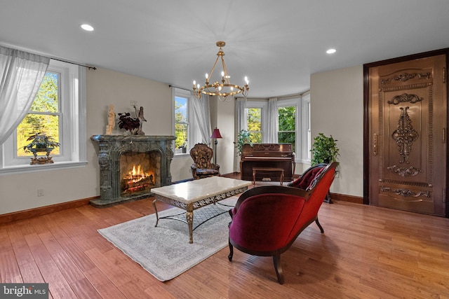 sitting room with an inviting chandelier, a premium fireplace, and light hardwood / wood-style floors