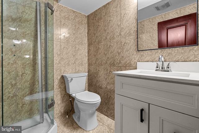 bathroom featuring tile walls, an enclosed shower, vanity, and toilet