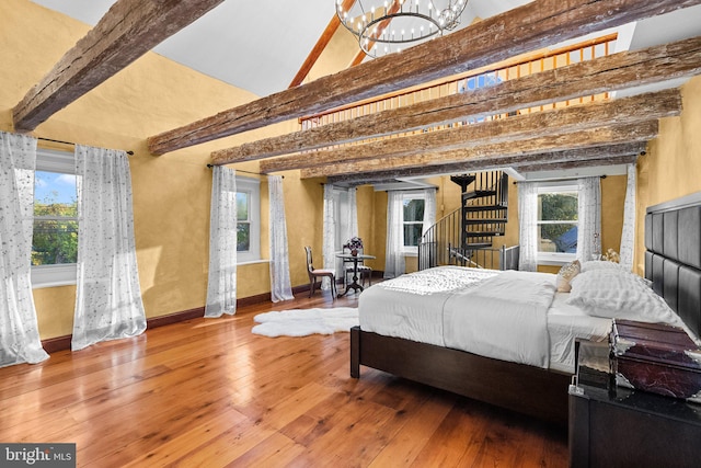 bedroom featuring multiple windows, wood-type flooring, a high ceiling, and beamed ceiling