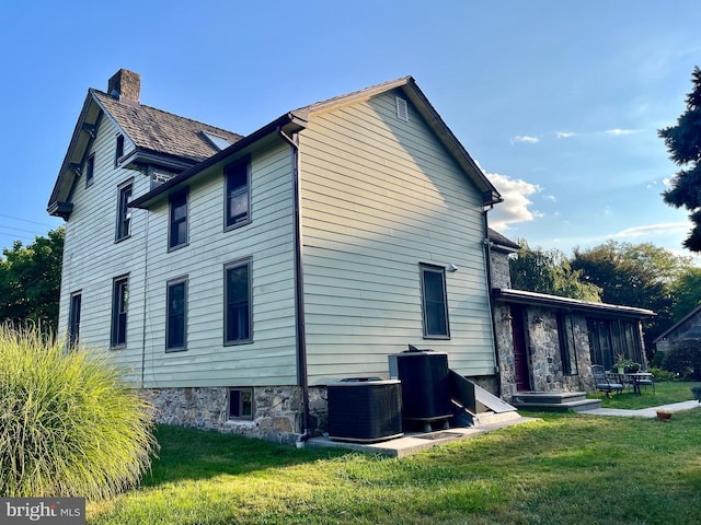 view of side of home featuring a yard and central air condition unit