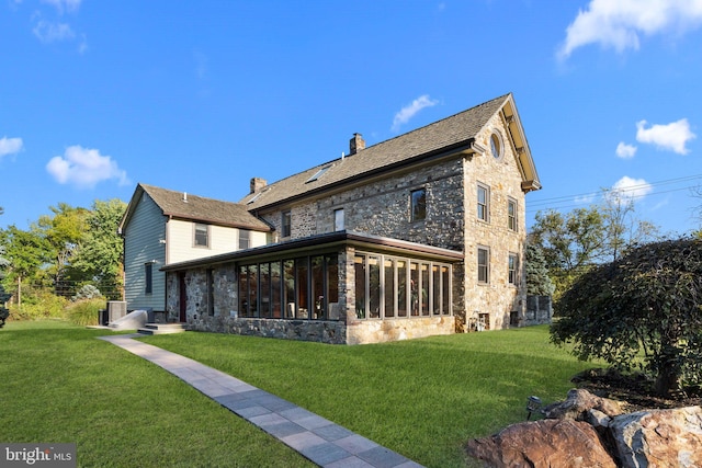 back of house featuring a sunroom and a lawn