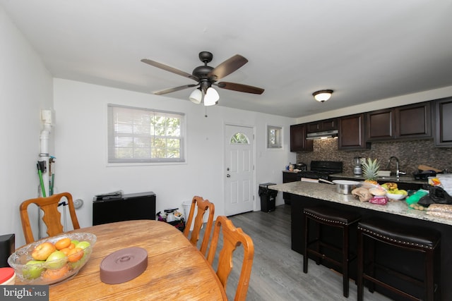 dining area featuring wood-type flooring, sink, and ceiling fan