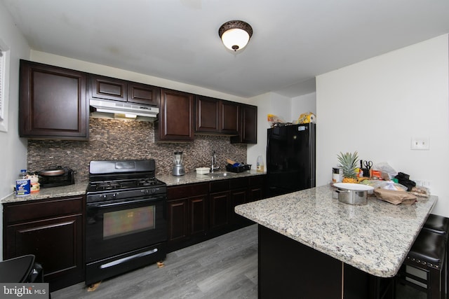 kitchen featuring sink, tasteful backsplash, black appliances, a breakfast bar, and light wood-type flooring