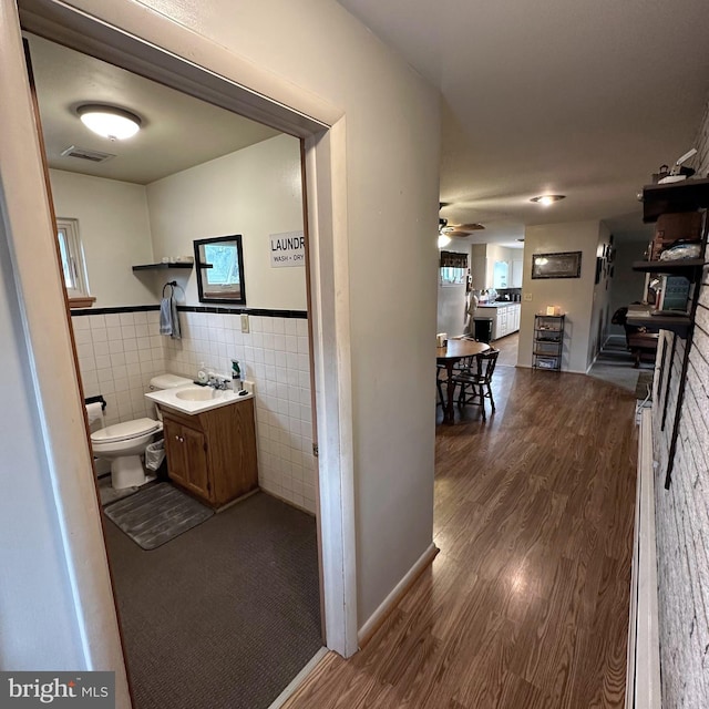 hall featuring sink, tile walls, and dark wood-type flooring