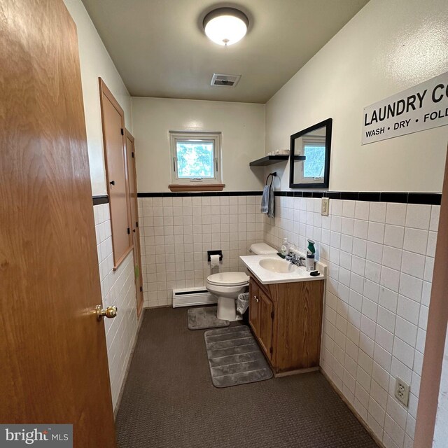 bathroom with a baseboard radiator, tile walls, vanity, and toilet