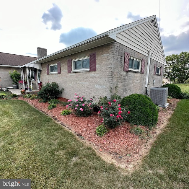 view of home's exterior with a sunroom, central AC, and a yard