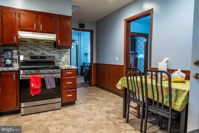 kitchen with stainless steel range oven, backsplash, and wood walls