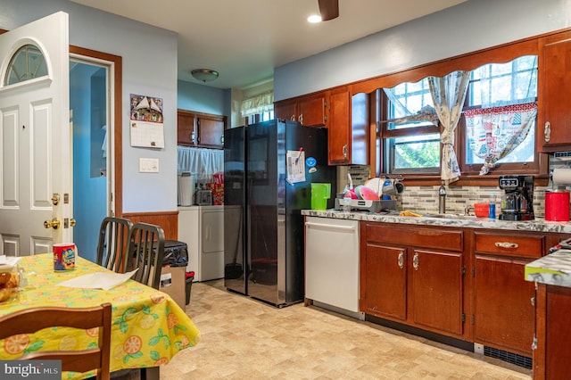 kitchen featuring decorative backsplash, stainless steel appliances, washing machine and clothes dryer, and sink