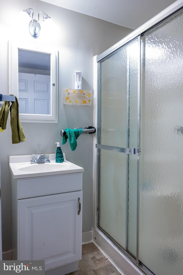 bathroom featuring a shower with shower door and vanity