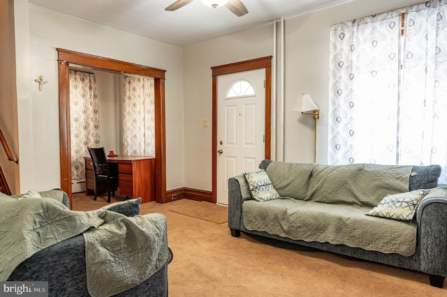 living room featuring a healthy amount of sunlight, a baseboard heating unit, light carpet, and ceiling fan